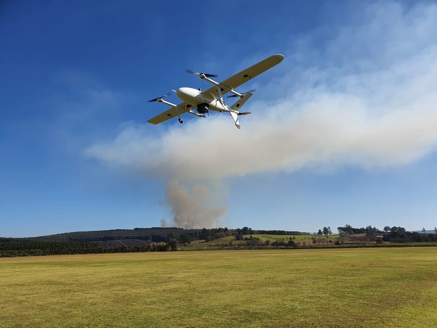Fixed-wing aircraft in flight past a smoke plume
